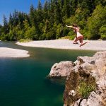 woman jumping into Chetco River