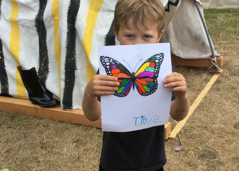 Child holding up drawing of butterfly